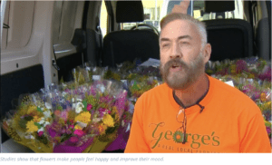 George from George's Flowers is interviewed in front of colorful flower bouquets