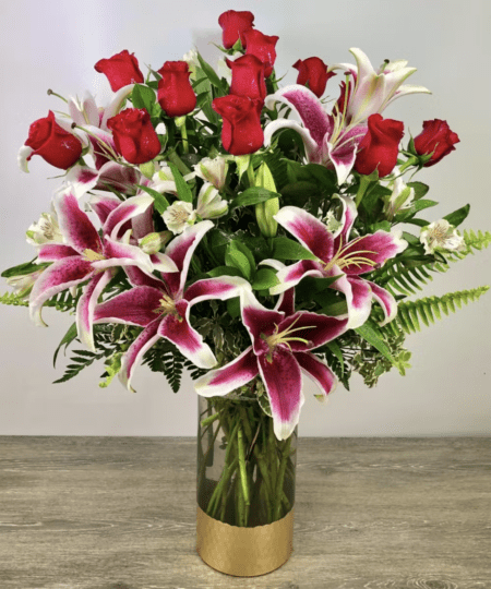 Our dozen roses, made even more luxurious! Red roses, as long-stem as they get are arranged in our tall, gold base scalloped cylinder vase. Upgrade to deluxe for the most show-stopping roses you've ever seen with alstromeria and stargazer lilies. Even more lilies than our George's Premium Dozen Roses! Send one today and see the smiles for yourself!